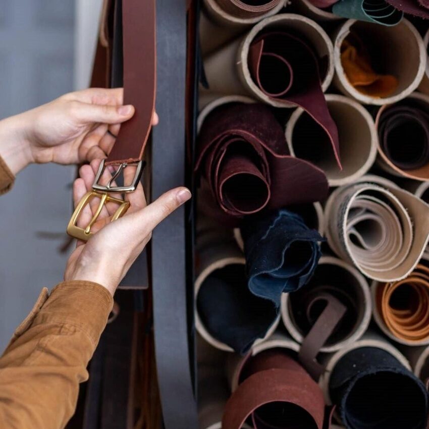 closeup hands professional tanner choosing belt buckle wooden table leather workshop closeup hands professional tanner 235376354